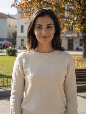 Jovana, 28-year-old Montenegrin woman from Podgorica with dark brown hair and cream sweater in autumn park